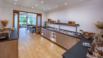 A modern breakfast area with wooden cabinets, a buffet counter, and a dining area with natural light.