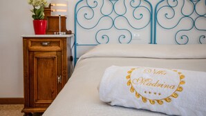 Un lit bien fait, avec un oreiller blanc et une serviette ornée d’un motif brodé.