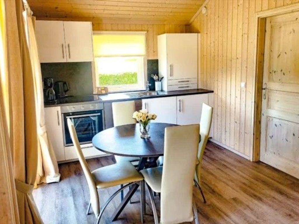 Uma cozinha compacta com mesa e cadeiras, uma janela e paredes de madeira.