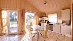 Una cocina compacta con comedor, paredes de madera y vista a través de la puerta.