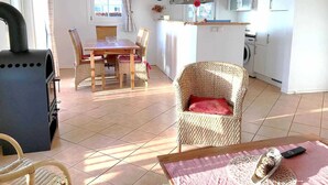 A spacious living area with a dining table, wicker chairs, a grill, and a kitchen with white cabinets.