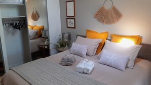 Un dormitorio ordenado con cama, almohadas y una mesita de noche.