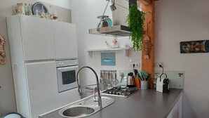 Una cocina moderna con horno empotrado, pileta de acero inoxidable y estufa a gas.
