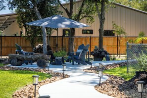 Un patio al aire libre con mobiliario, una sombrilla grande y un sendero.