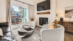 A modern living room with a fireplace, a sofa, a coffee table, and a TV mounted on the wall. - Free SkyCard Act 2-Level Condo + Loft, Outdoor Pool/Hot Tubs-Lances West 7 (Breckenridge)