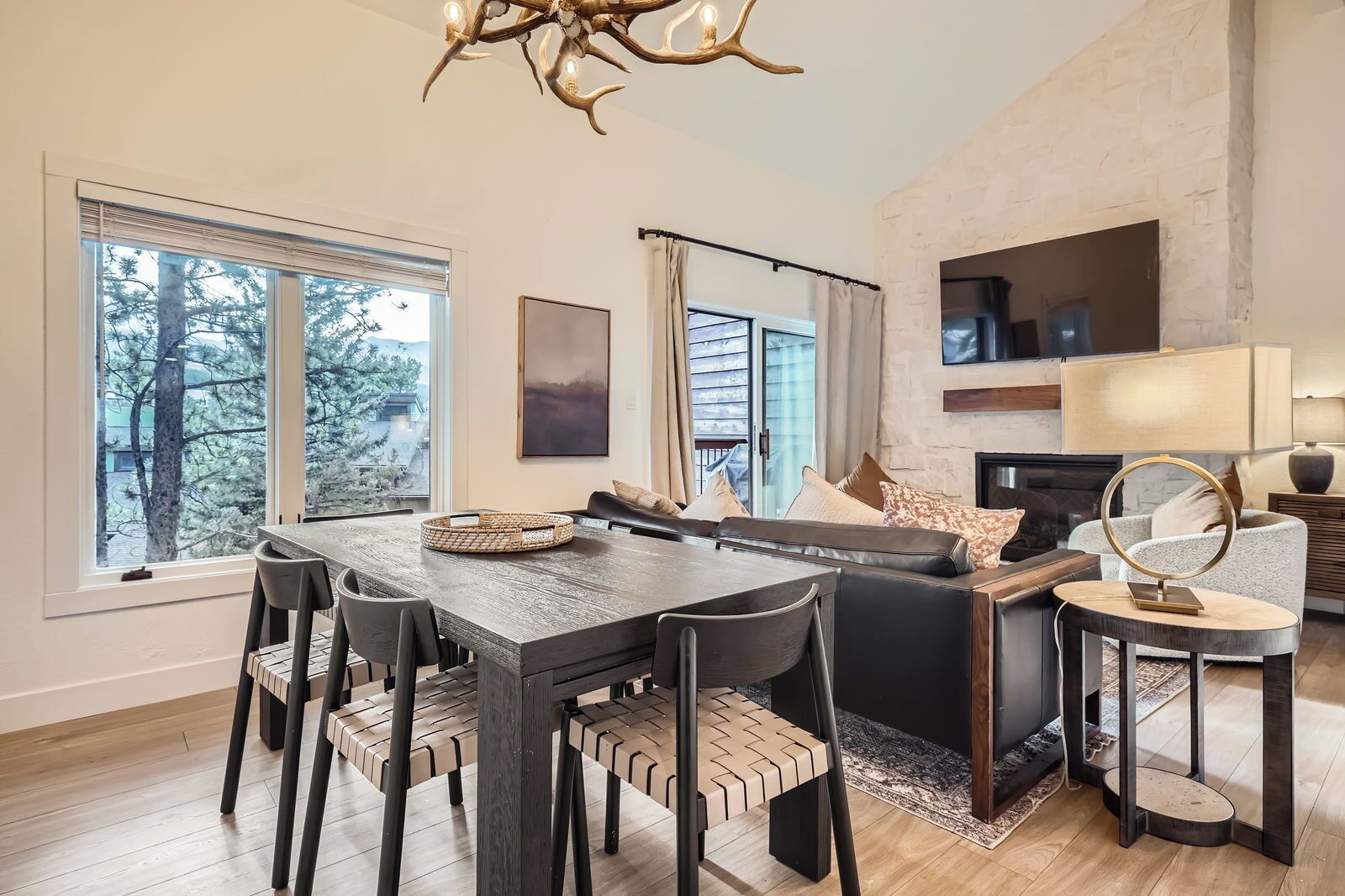 Una sala moderna con comedor, ventanas amplias, chimenea y una pared decorativa de piedra.