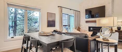 Una sala moderna con comedor, ventanas amplias, chimenea y una pared decorativa de piedra.