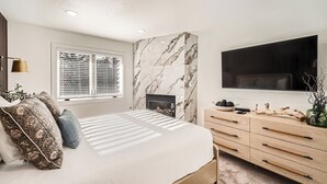 A bedroom with a bed, a fireplace, a TV, and a dresser. - Free SkyCard Act 2-Level Condo + Loft, Outdoor Pool/Hot Tubs-Lances West 7 (Breckenridge)
