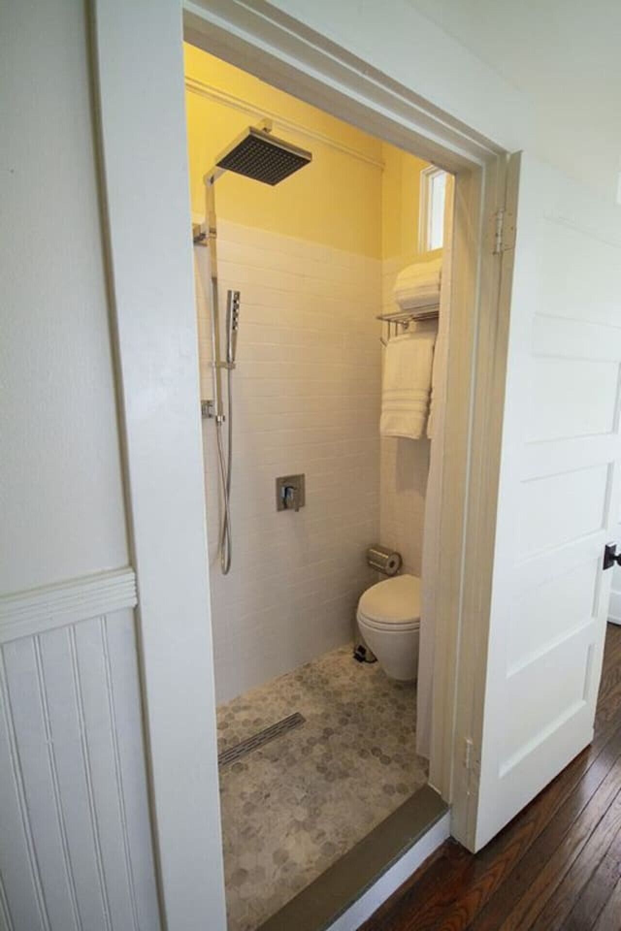Une petite salle de bain comprenant une douche, des toilettes et un porte-serviettes.