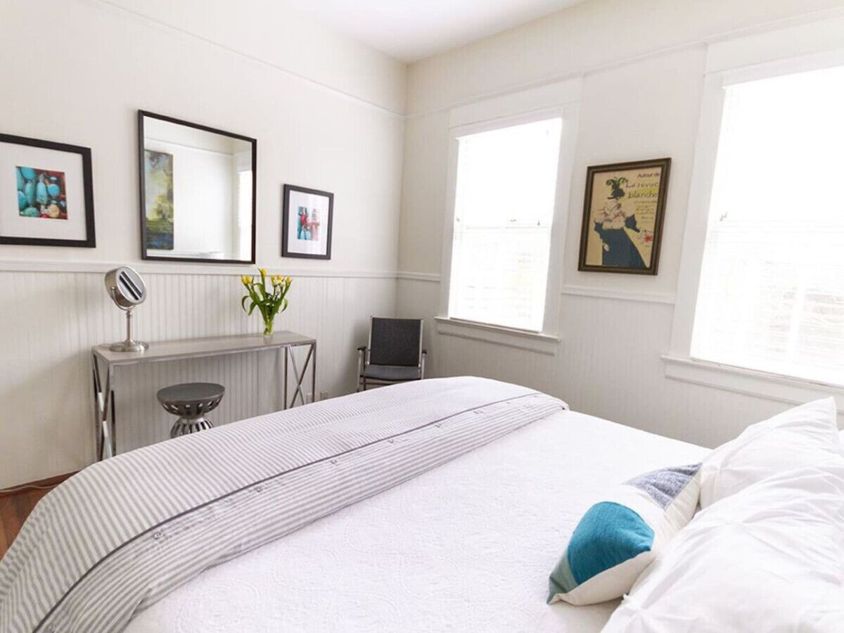 A bedroom with a bed, a desk, a chair, and a radiator.
