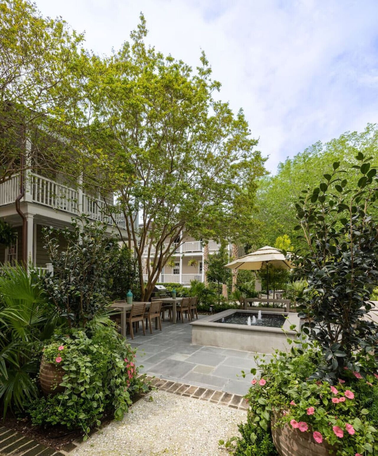A courtyard with a fountain, outdoor seating, and lush greenery.