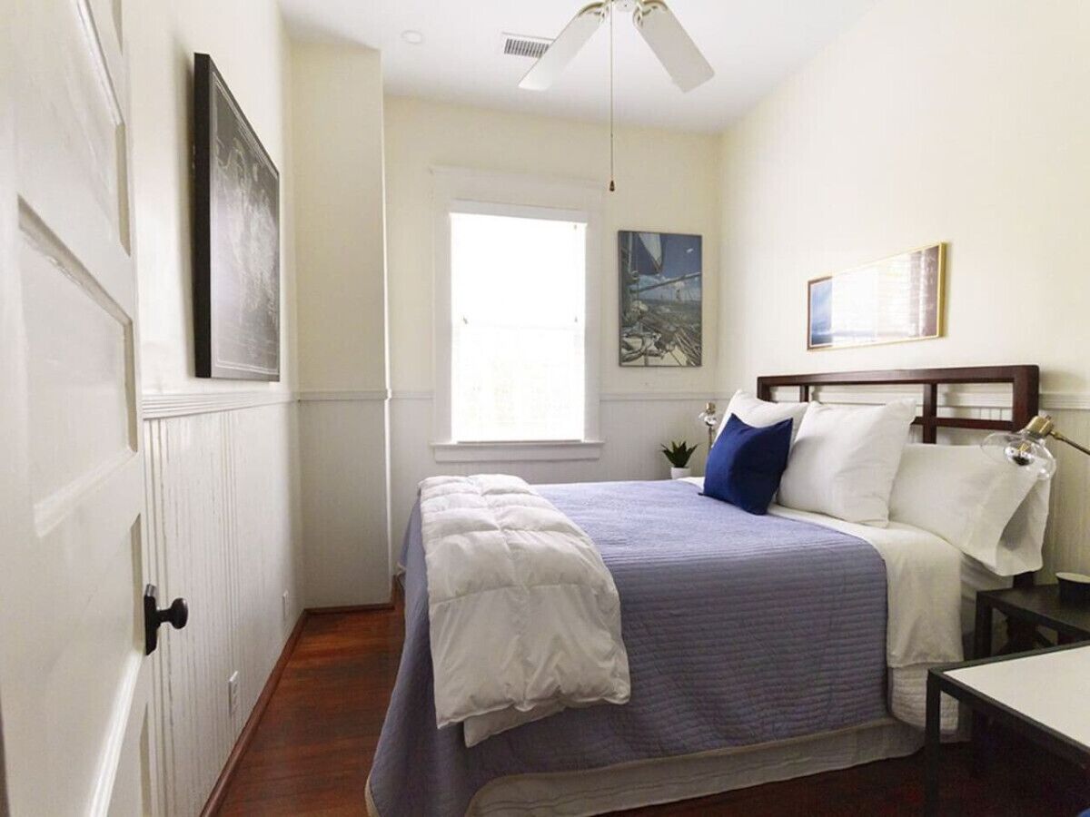 Un dormitorio con cama, ventana, ventilador de techo y puerta.