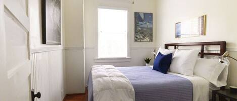 Un dormitorio con cama, ventana, ventilador de techo y puerta.