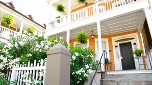 Une maison à deux étages avec un porche, des balustrades blanches et des plantes en pot.