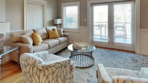 A living room with a sofa, armchairs, a coffee table, and a ceiling fan. - Brass Rail 206 | 30 Yards to Beach, Shared Pool (Tybee Island)