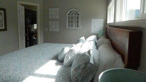 A bedroom with a bed, pillows, a nightstand, a window, and a door. - Mt Defiance Cabin with Columbia River View (Stevenson)