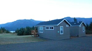 A two-story house with a deck, surrounded by a gravel driveway, with mountains in the background. - Mt Defiance Cabin with Columbia River View (Stevenson)