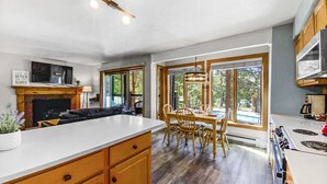 Une cuisine spacieuse dotée d’un grand îlot central, de meubles en bois et d’un coin repas offrant une vue sur l’extérieur.