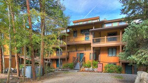Un immeuble en bois à plusieurs étages, doté de balcons, une allée gravillonnée et des arbres tout autour.