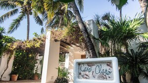 A sign with "Calai Clara" written on it, surrounded by lush greenery and palm trees.