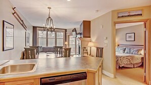 A modern kitchen with a central island, built-in dishwasher, and a dining area with a round table and chairs. - River Run Condo, 200 yards to gondola, Slope Views, Heated Garage, Free WiFi (Keystone)