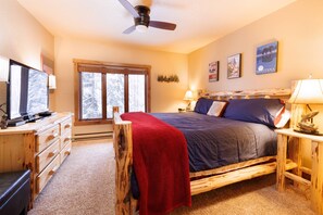 A cozy bedroom with a bed, wooden dresser, and a television.