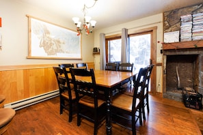 A dining room with a wooden table and chairs, a chandelier, a fireplace, and a large map on the wall.