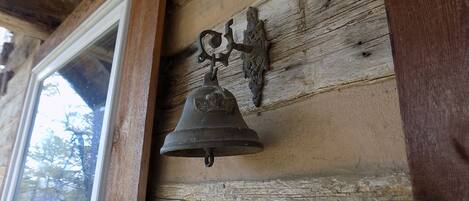 Un mur en bois rustique, sur lequel est fixée une vieille cloche en métal.