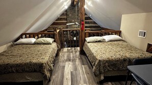 Un dormitorio acogedor en el ático, con dos camas, suelo de madera y techo inclinado con vigas a la vista.