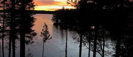Um lago tranquilo ao pôr do sol, com árvores emoldurando a paisagem.