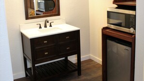 Une salle de bain équipée d’un meuble-lavabo, d’un évier, d’un miroir et d’un four à micro-ondes.