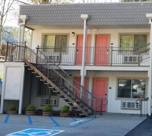 Stunning two-story building with a central staircase and patterned roof, featuring a red door and potted plants.