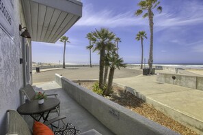 A balcony with a view of the ocean, palm trees, and a 'No Smoking' sign.