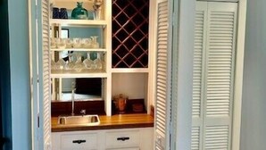 Una cocina compacta con armarios blancos, un espacio para vinos empotrado y una pequeña encimera.