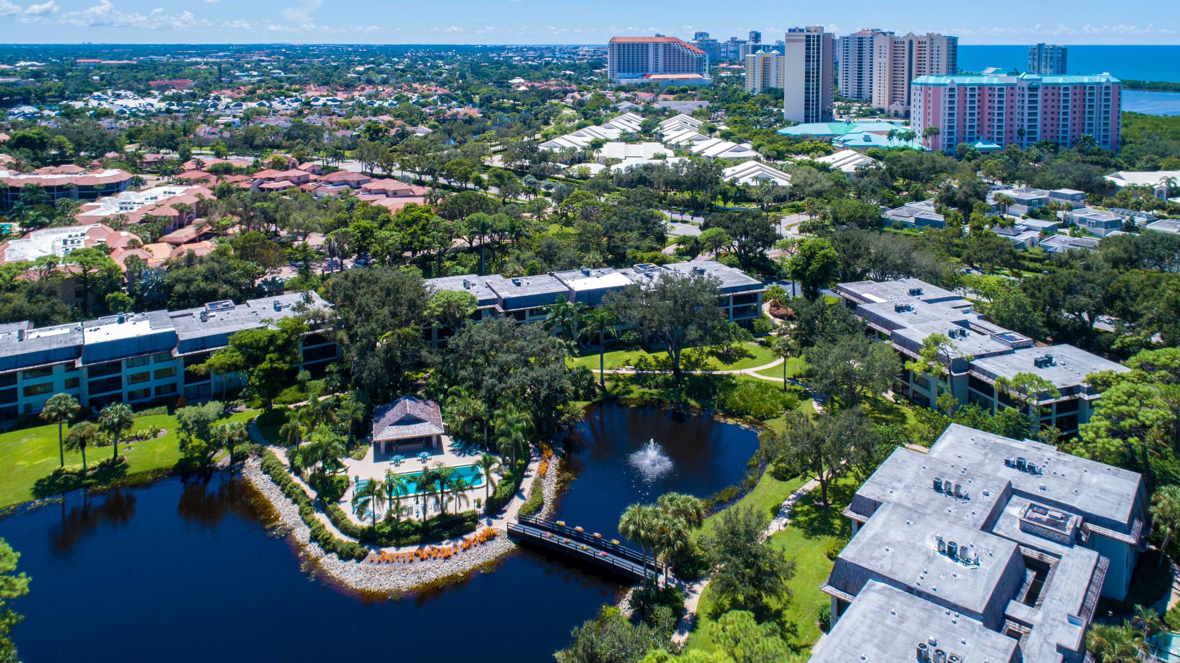 An aerial view of a resort area with a central water feature, multiple buildings, and a bridge.