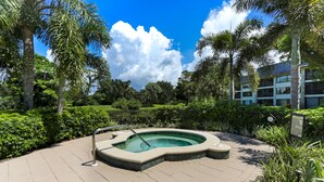 Un jacuzzi rodeado de vegetación exuberante y un cielo azul despejado.