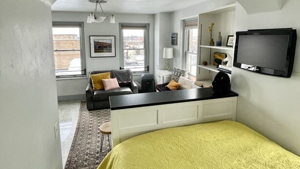 Un espacio habitable compacto con una cama, un sofá, un escritorio y un televisor.