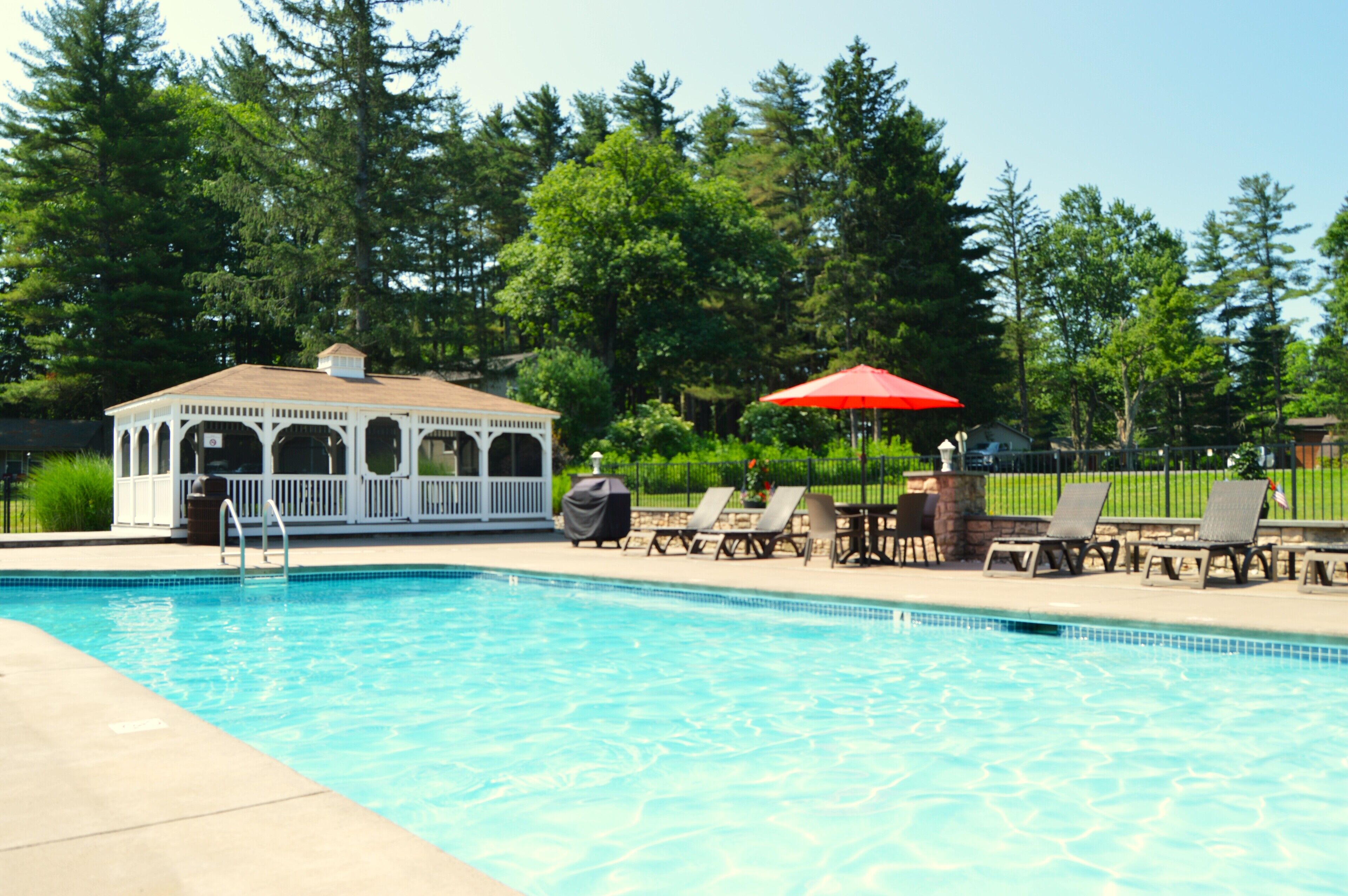 A swimming pool with lounge chairs and a gazebo.