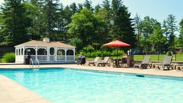 A swimming pool with lounge chairs and a gazebo.