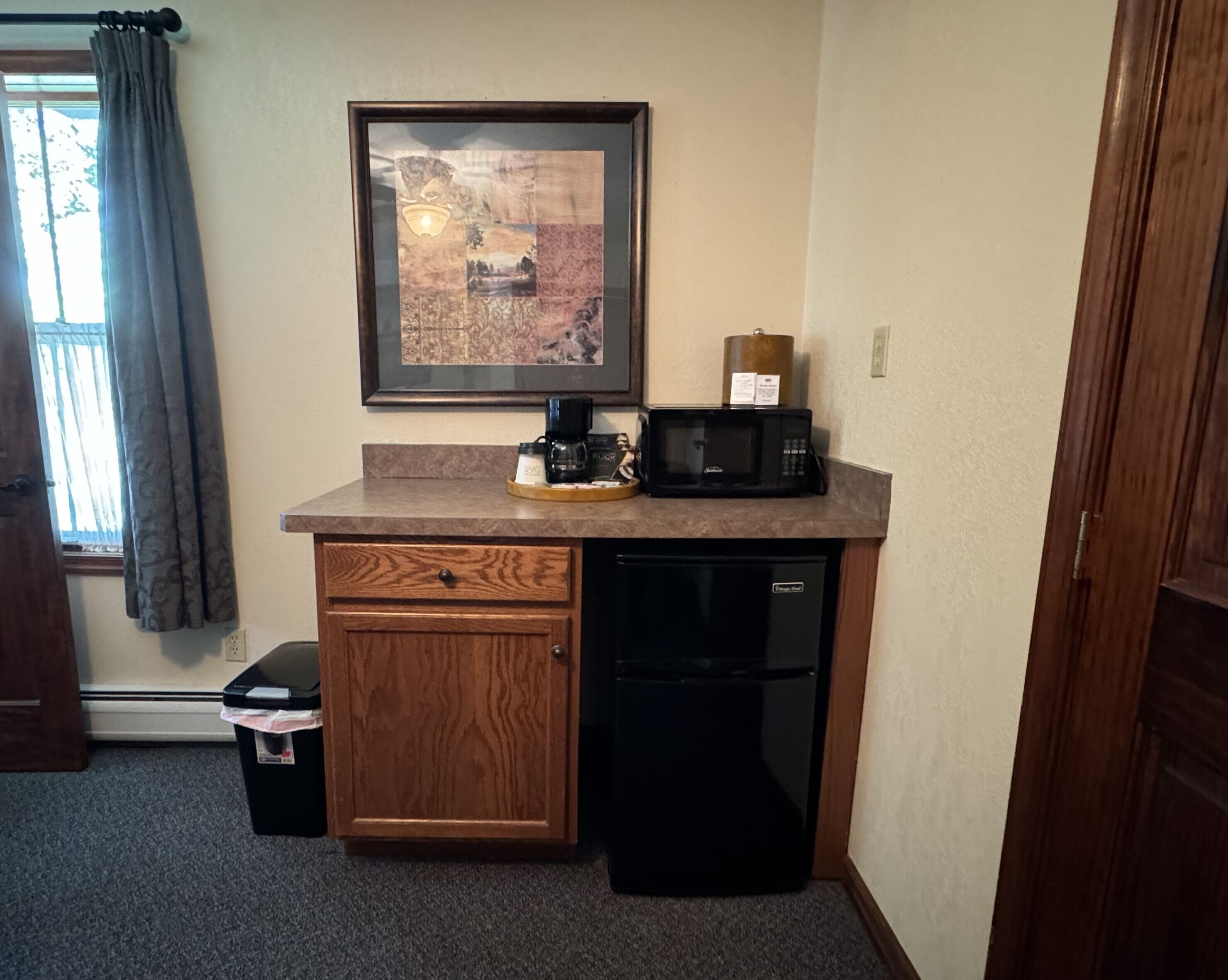 A compact kitchenette with a coffee maker, microwave, and a small refrigerator.