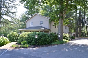 A two-story building with a covered porch, surrounded by dense greenery and trees. - Woodfield Manor, A Sundance Vacations Property (Mount Pocono)