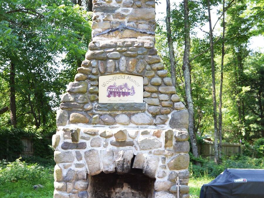 A stone fireplace with two wooden Adirondack chairs in front.