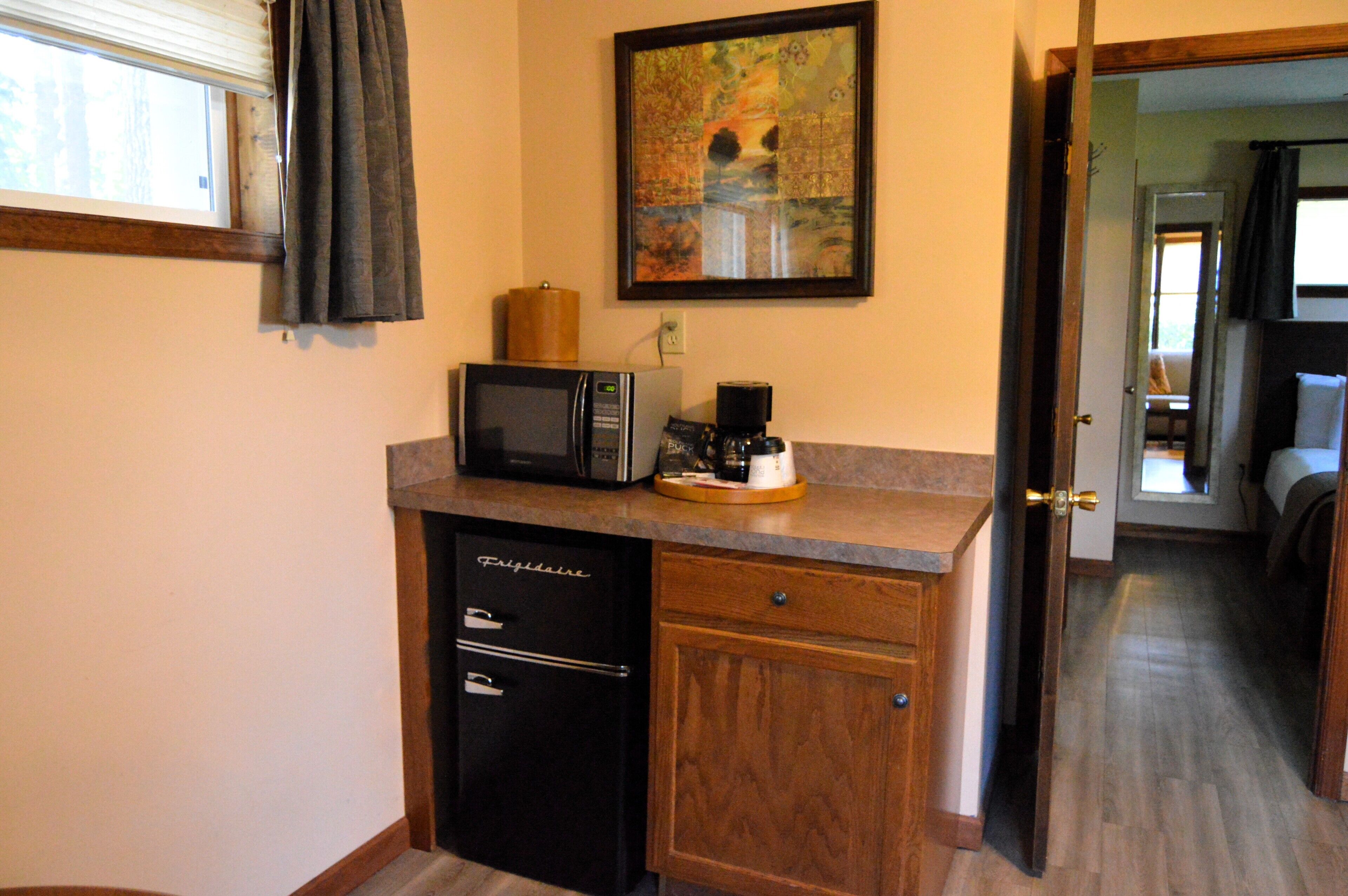 A compact kitchen with a microwave, coffee maker, and a small refrigerator.