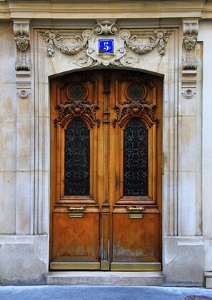 A double wooden door with intricate carvings and a blue sign above it. - Ideal address for a Paris visitor, refurbished, fine amenities & furniture. (Paris)