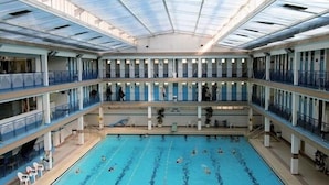A multi-level indoor swimming pool with clear lanes and a glass ceiling.
