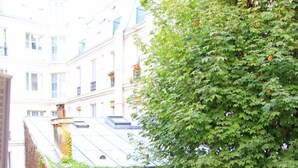 A building with a balcony and a tree with green leaves.