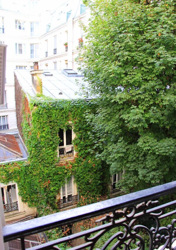 A building with a balcony and a tree with green leaves.