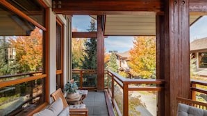 Un balcon avec des balustrades en bois, un banc rembourré et une petite table agrémentée d’une plante.
