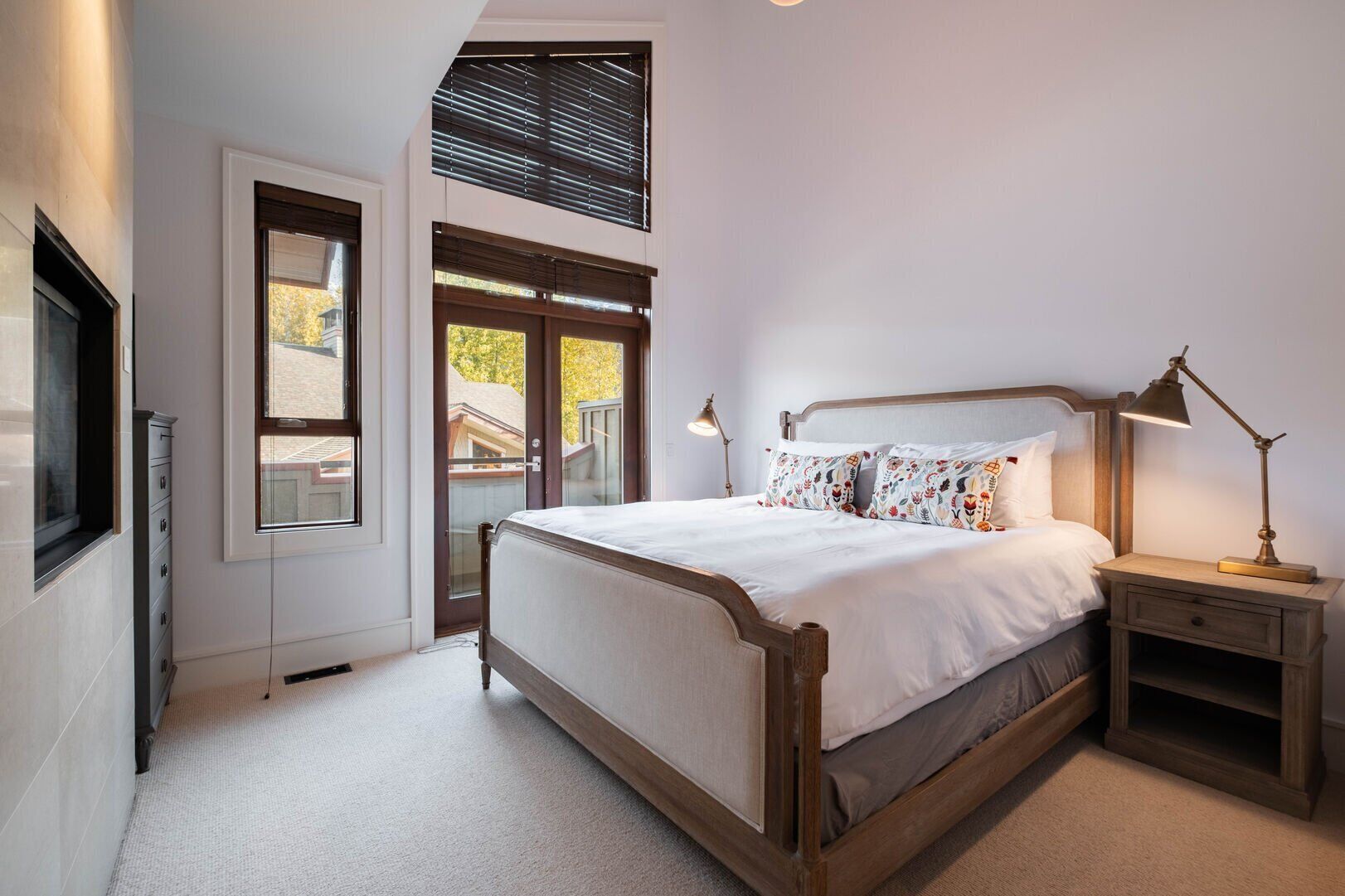 A bedroom with a bed, bedside tables, a window, and a door.