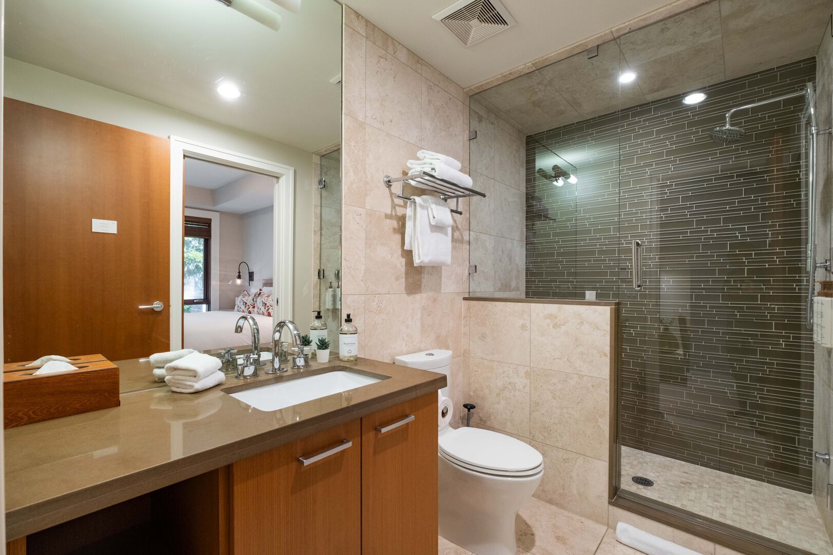 A modern bathroom with a large sink, mirror, and shower area.